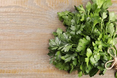 Photo of Bunch of fresh green parsley leaves on light wooden table. Space for text