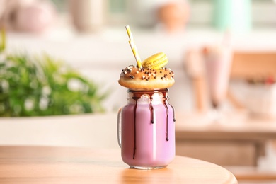 Mason jar with delicious milk shake on table against blurred background