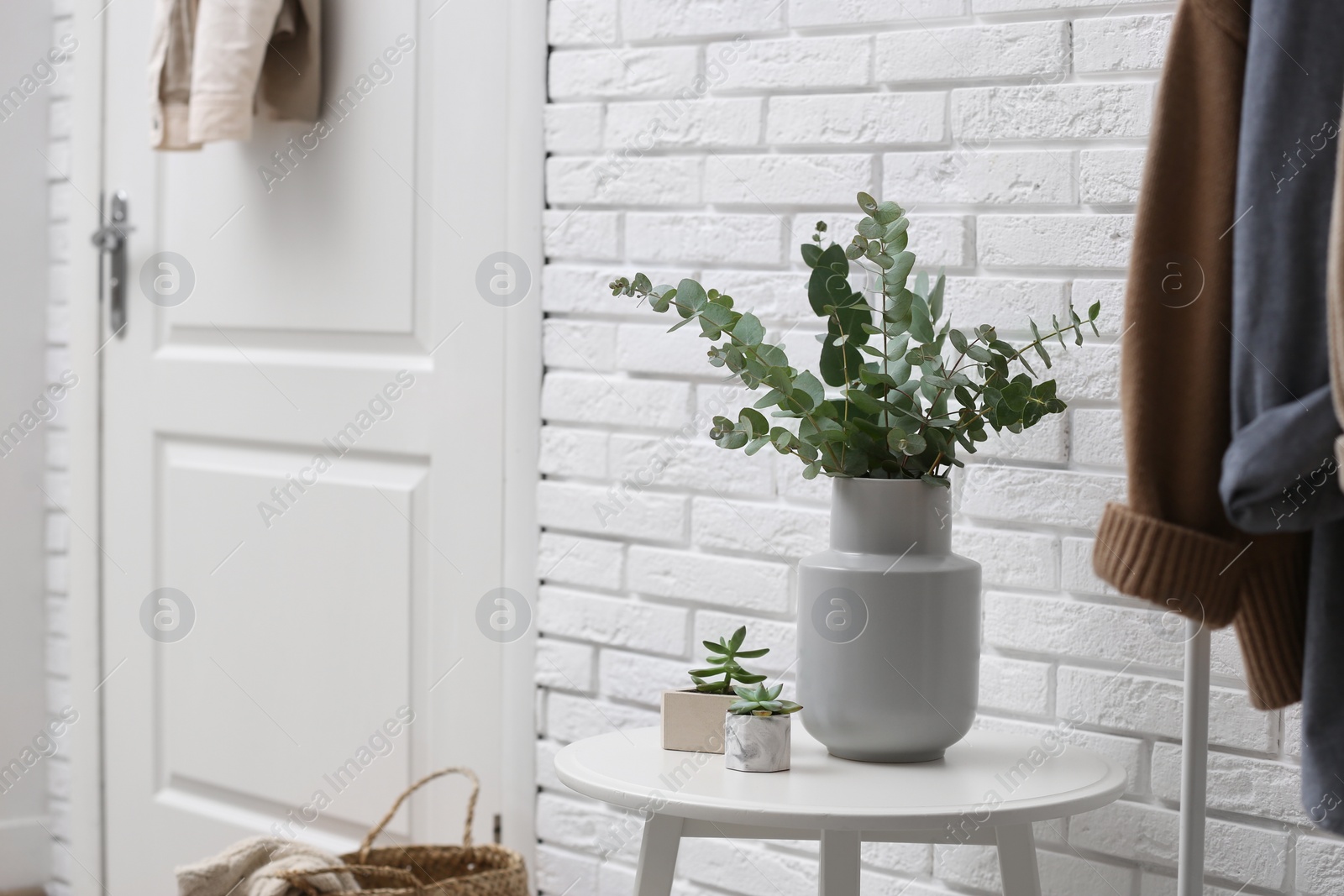 Photo of Vase with fresh eucalyptus branches on table in entryway. Interior design