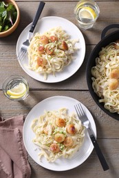 Photo of Delicious scallop pasta with onion served on wooden table, flat lay