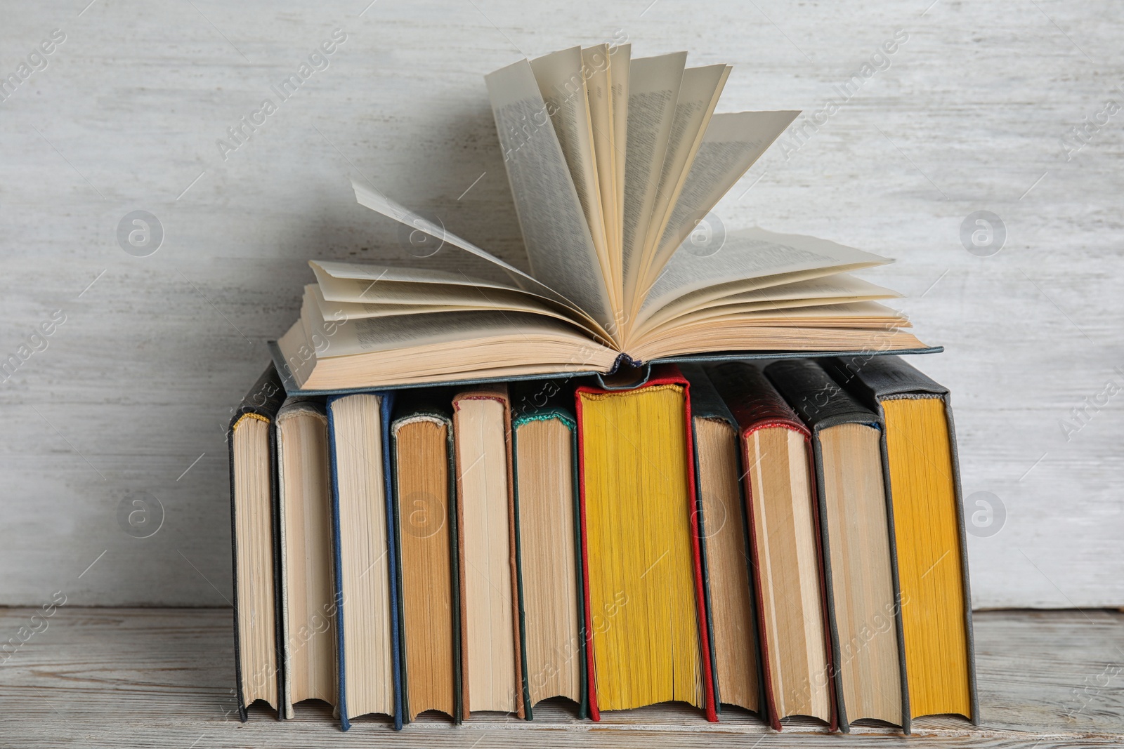 Photo of Stack of hardcover books on wooden table against white background