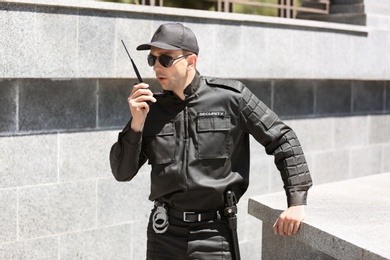 Photo of Male security guard using portable radio transmitter outdoors