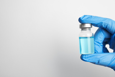 Doctor holding vial with medication on white background, closeup view and space for text. Vaccination and immunization