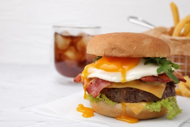 Photo of Delicious burger with fried egg on white table, closeup. Space for text