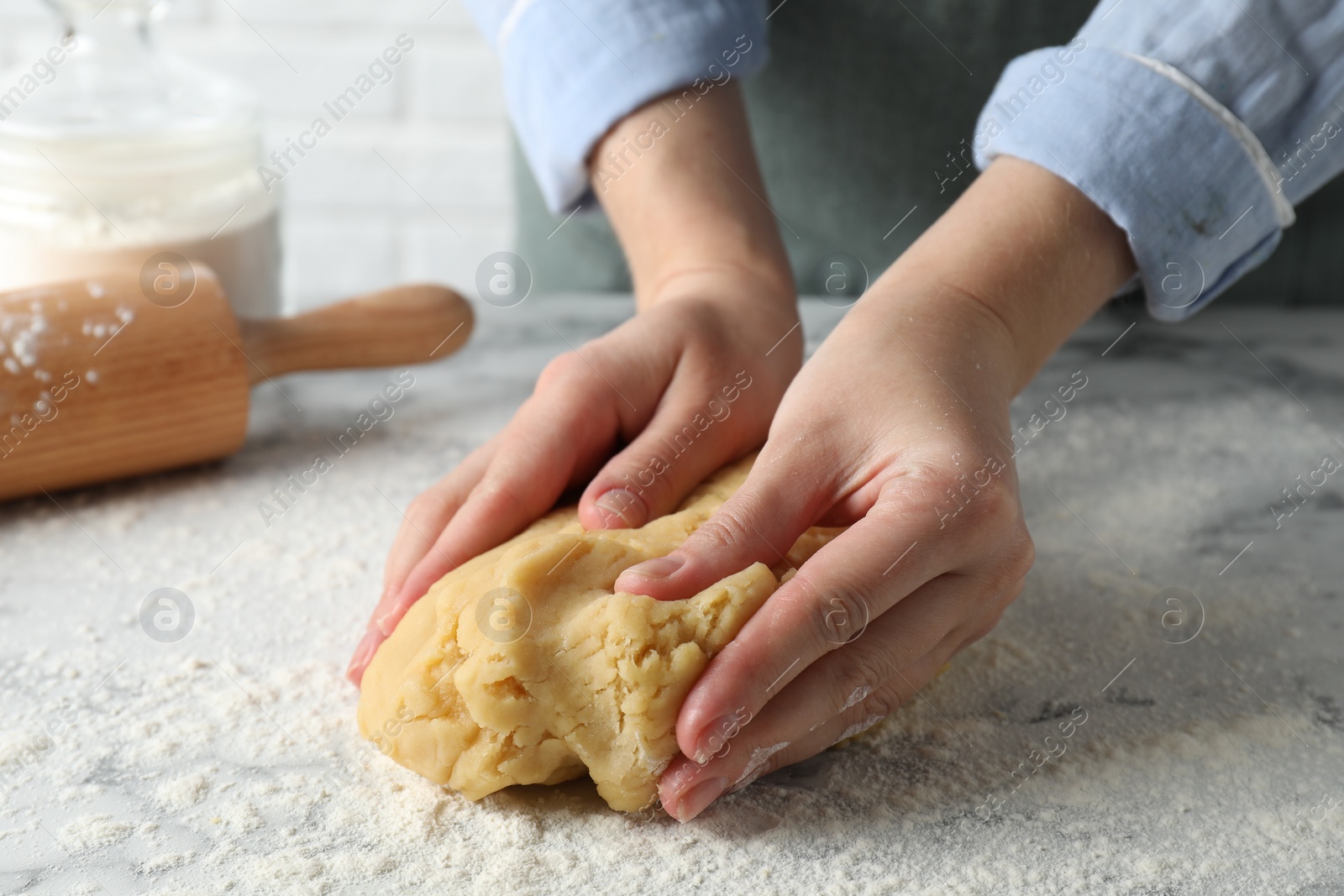 Photo of Making shortcrust pastry. Woman kneading raw dough at white marble table, closeup