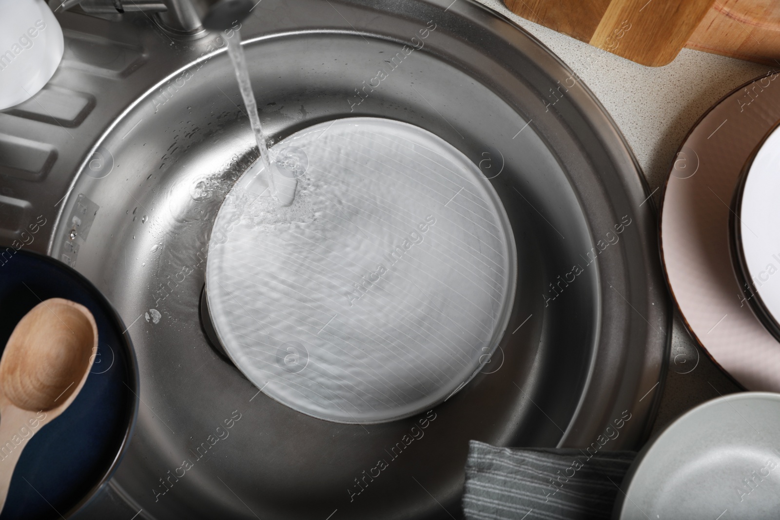 Photo of Washing plate in kitchen sink, above view