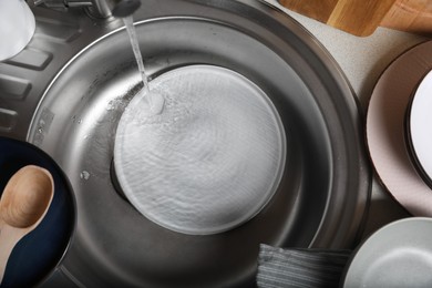 Photo of Washing plate in kitchen sink, above view