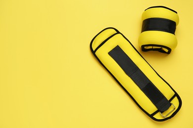 Stylish weighting agents on yellow background, flat lay. Space for text