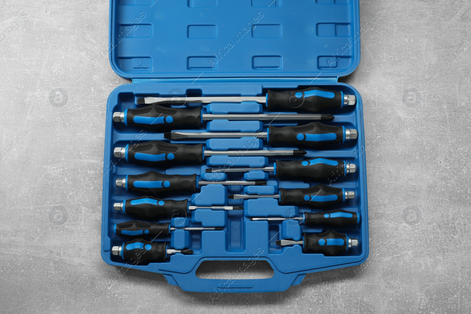 Photo of Set of screwdrivers in open toolbox on grey textured table, top view