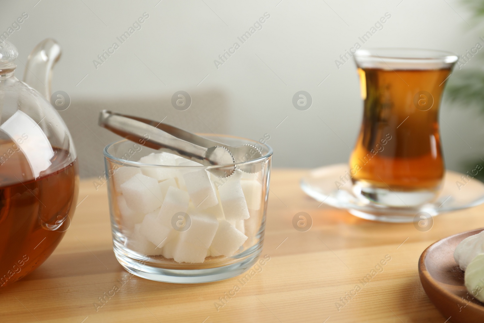 Photo of Sugar cubes and aromatic tea in glass on wooden table