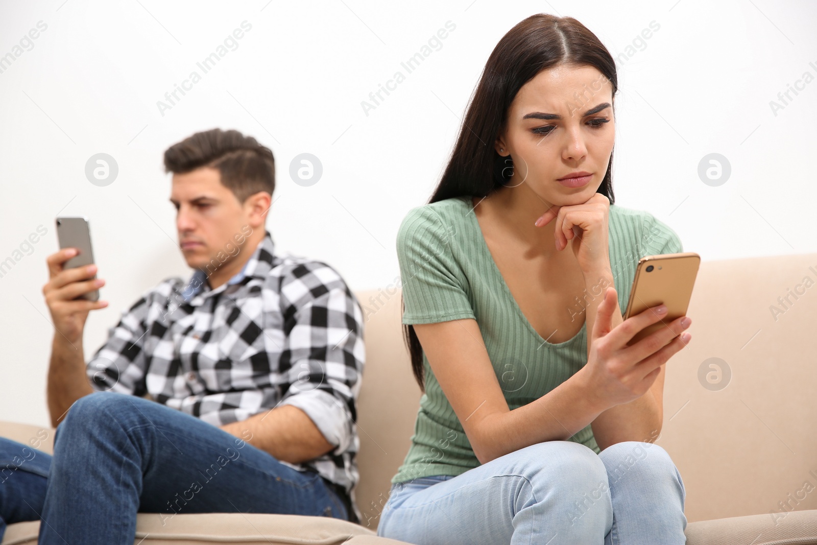 Photo of Couple addicted to smartphones ignoring each other at home. Relationship problems