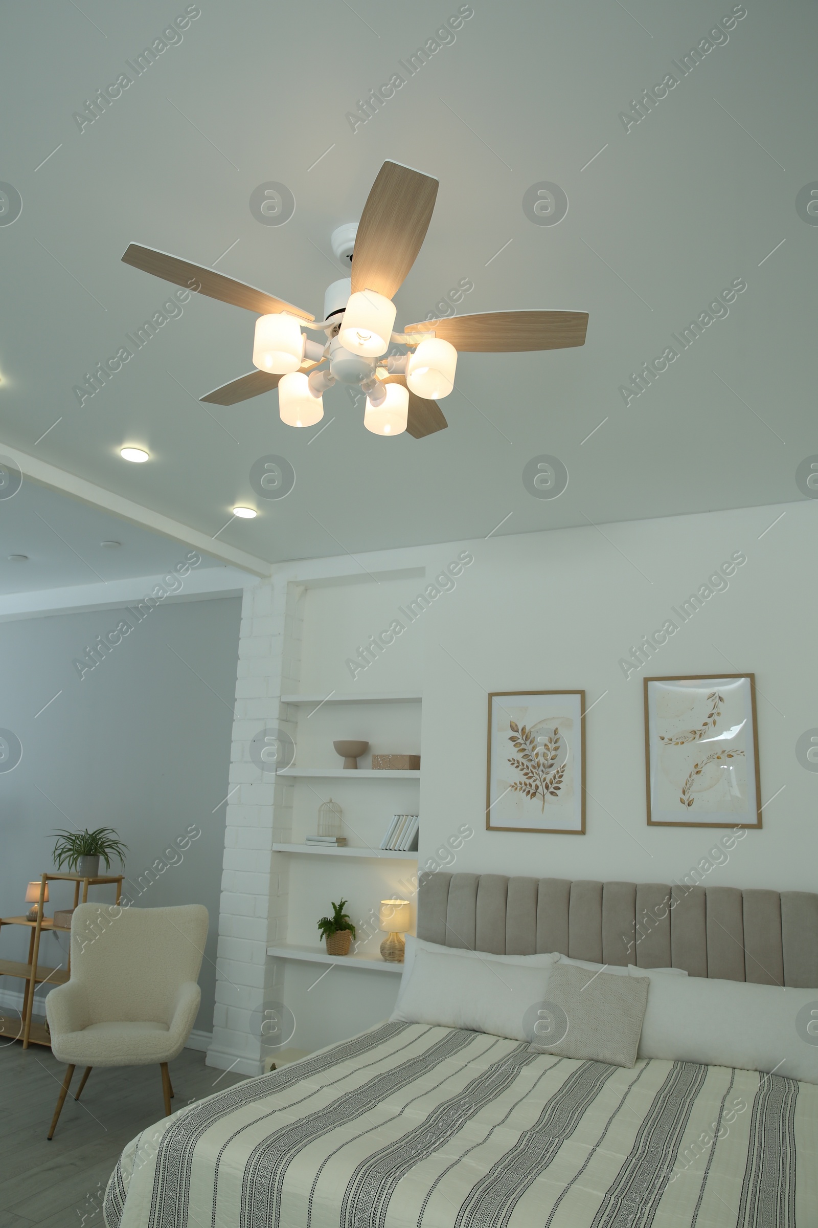 Photo of Ceiling fan, furniture and houseplants in stylish bedroom