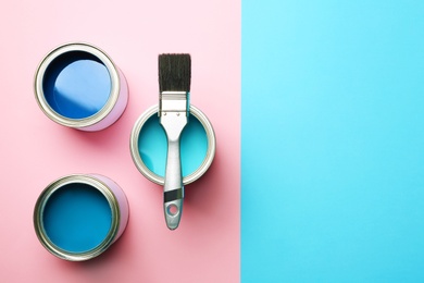 Photo of Open paint cans, brush and space for text on color background, top view