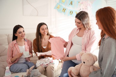 Happy pregnant woman spending time with friends at baby shower party