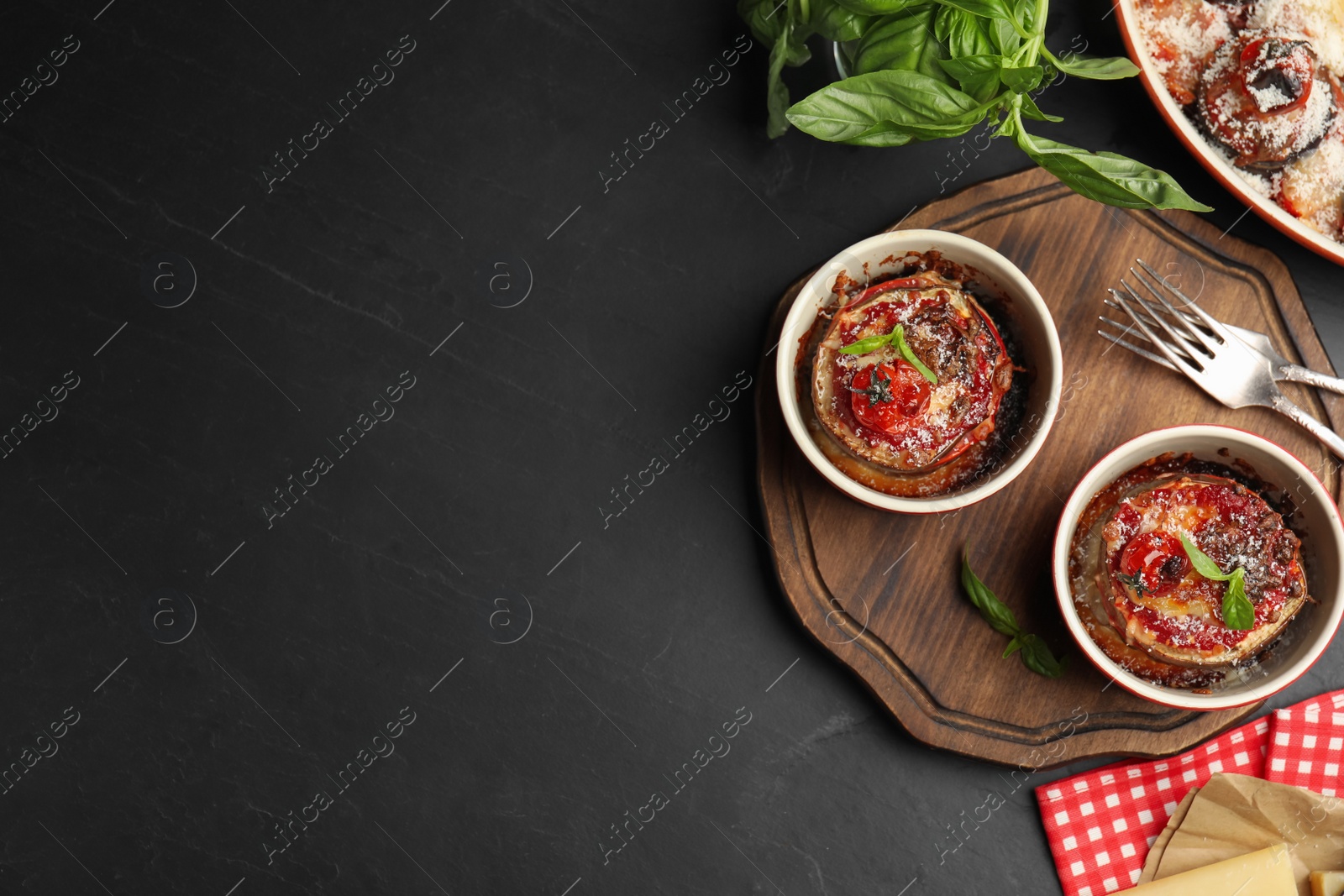 Photo of Baked eggplant with tomatoes, cheese and basil served on black table, flat lay. Space for text