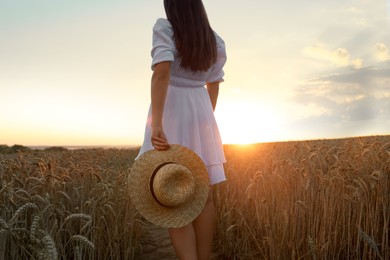 Photo of Beautiful young woman with straw hat in ripe wheat field at sunset, closeup