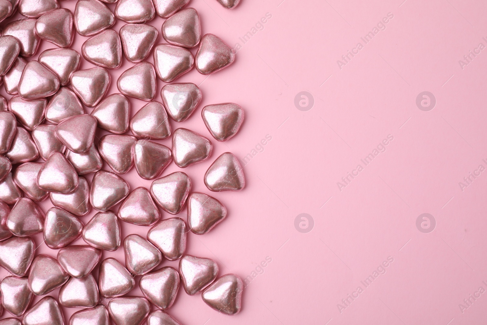 Photo of Many delicious heart shaped candies on pink background, flat lay. Space for text