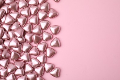 Many delicious heart shaped candies on pink background, flat lay. Space for text
