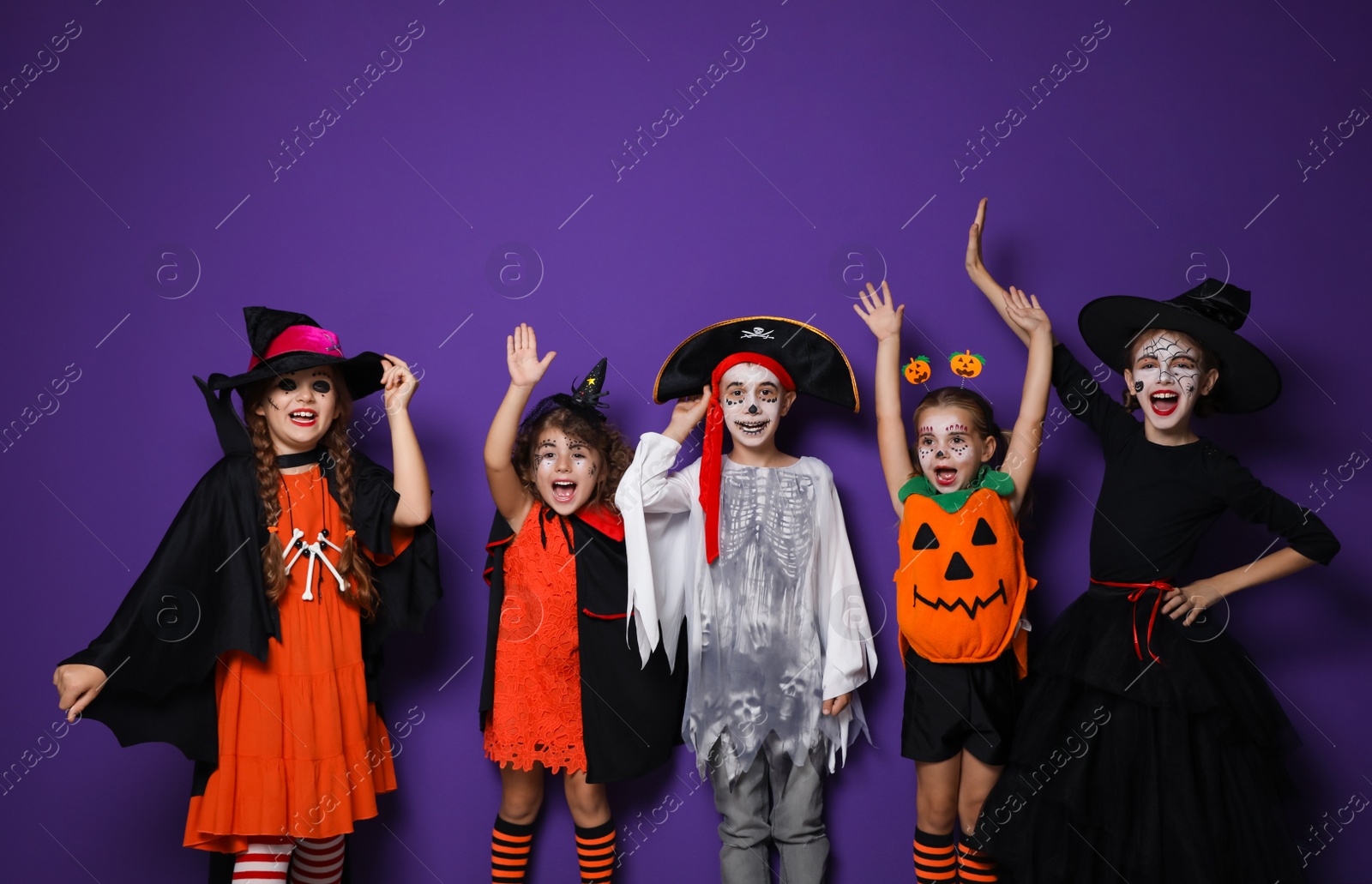Photo of Cute little kids wearing Halloween costumes on purple background