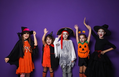 Photo of Cute little kids wearing Halloween costumes on purple background