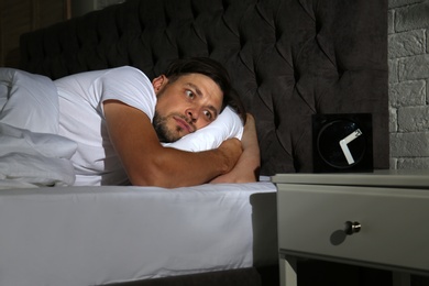 Man suffering from insomnia in bed at home