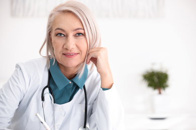 Portrait of mature female doctor in white coat at workplace