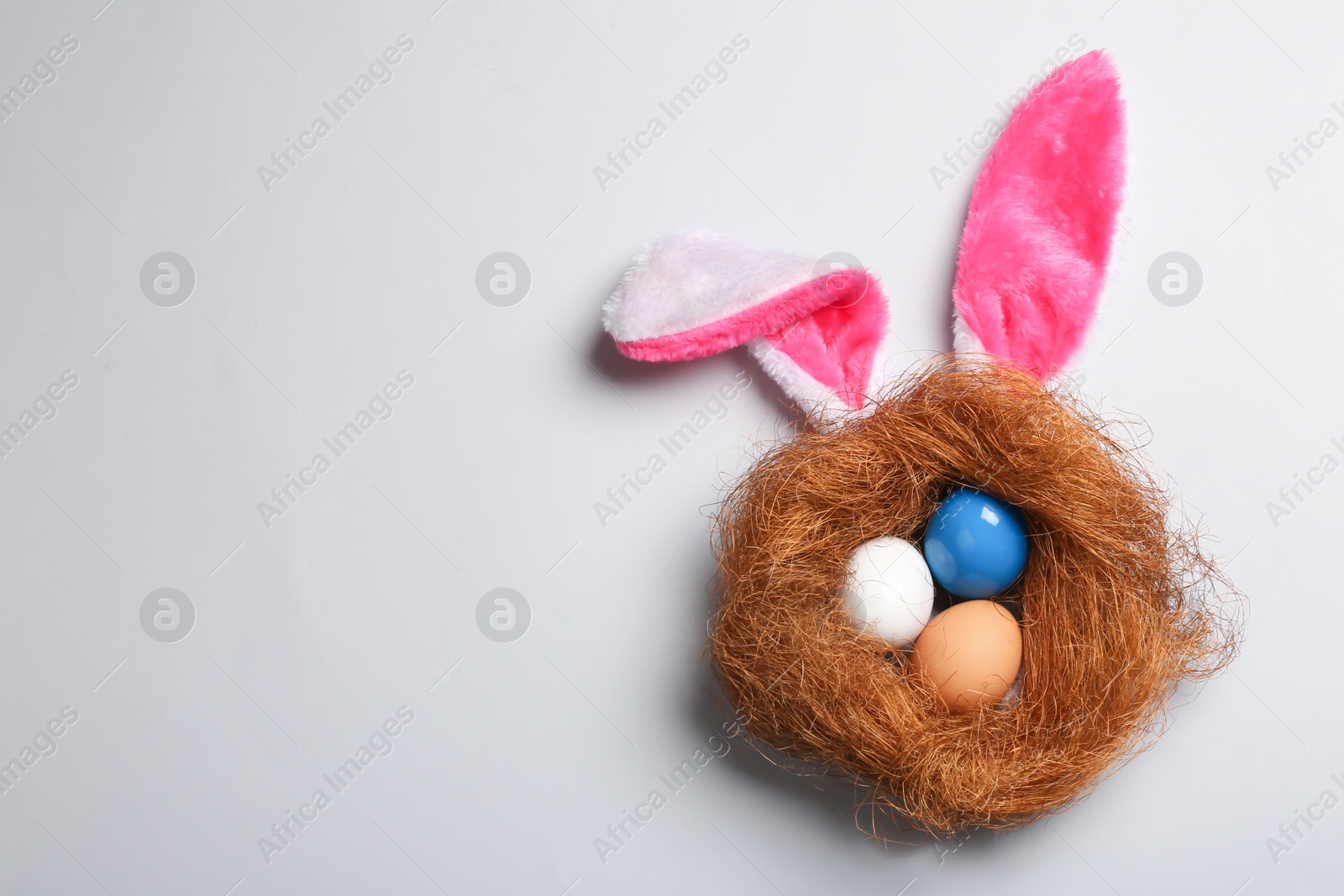 Photo of Flat lay composition of Easter bunny ears with eggs on color background, space for text