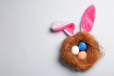 Photo of Flat lay composition of Easter bunny ears with eggs on color background, space for text