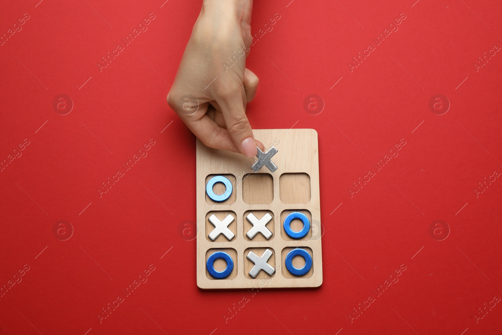 Photo of Woman playing tic tac toe game on red background, top view