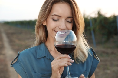 Young beautiful woman enjoying wine at vineyard