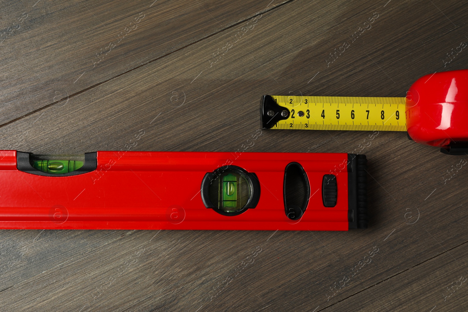 Photo of Building level and tape measure on wooden table, top view