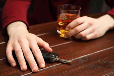 Photo of Drunk man reaching for car keys at table, closeup. Don't drink and drive concept