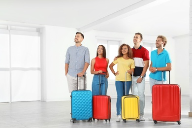 Photo of Group of young people with suitcases in light room