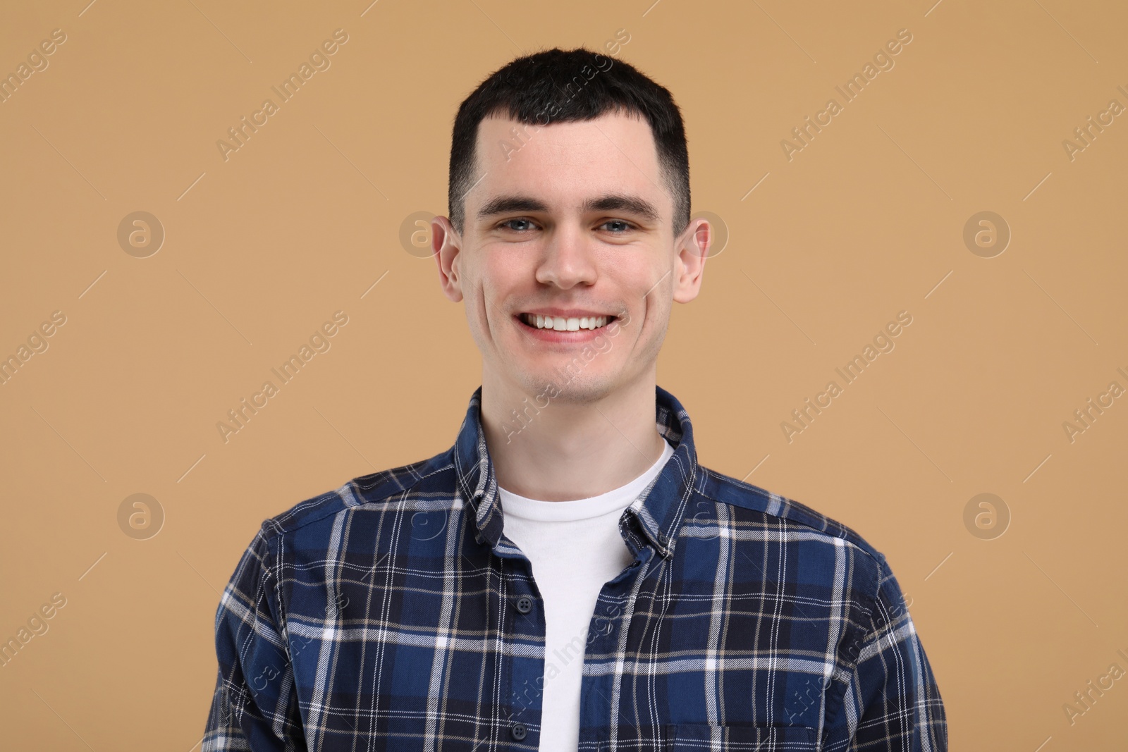 Photo of Handsome young man with clean teeth smiling on beige background