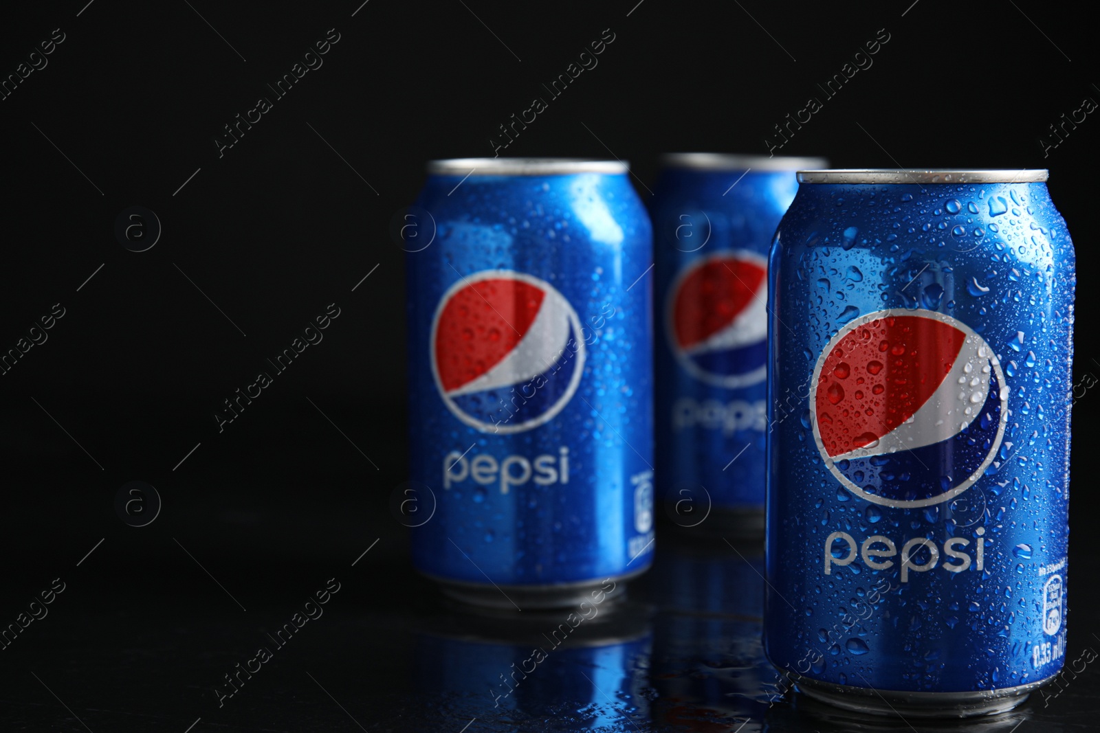 Photo of MYKOLAIV, UKRAINE - FEBRUARY 08, 2021: Cans of Pepsi with water drops on black table, space for text