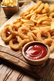 Photo of Bowl tasty ketchup and different snacks on wooden table, closeup
