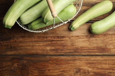 Photo of Basket with ripe zucchinis on wooden table, flat lay. Space for text