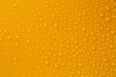 Photo of Water drops on orange background, top view