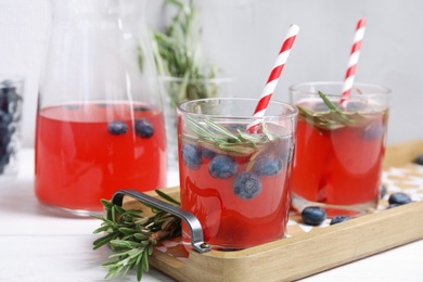 Photo of Tasty refreshing blueberry cocktail with rosemary on table