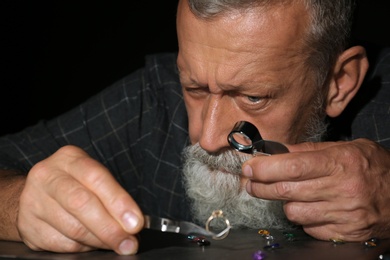 Photo of Male jeweler evaluating diamond ring in workshop, closeup view