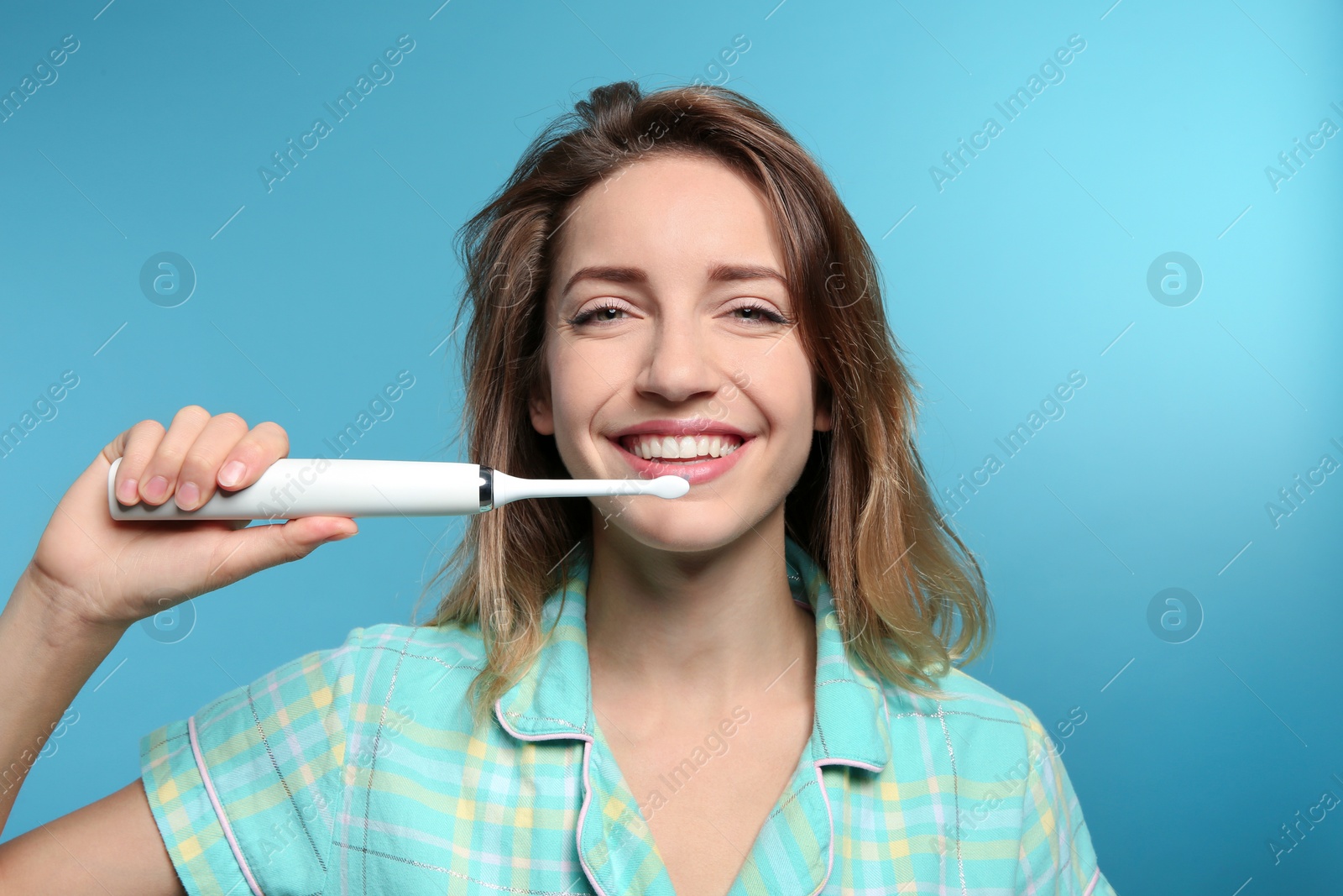 Photo of Portrait of young woman with electric toothbrush on color background