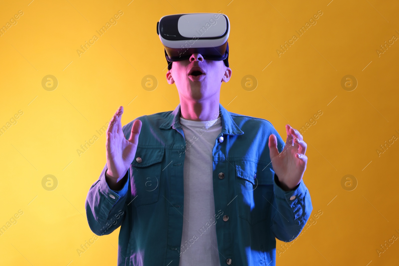 Photo of Young man with virtual reality headset on yellow background. Space for text