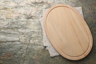 Photo of Wooden cutting board and napkin on textured table, top view. Space for text