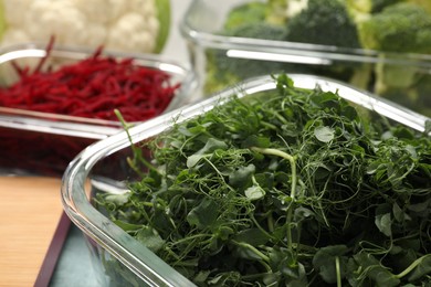 Photo of Glass container with microgreens on table, closeup. Food storage