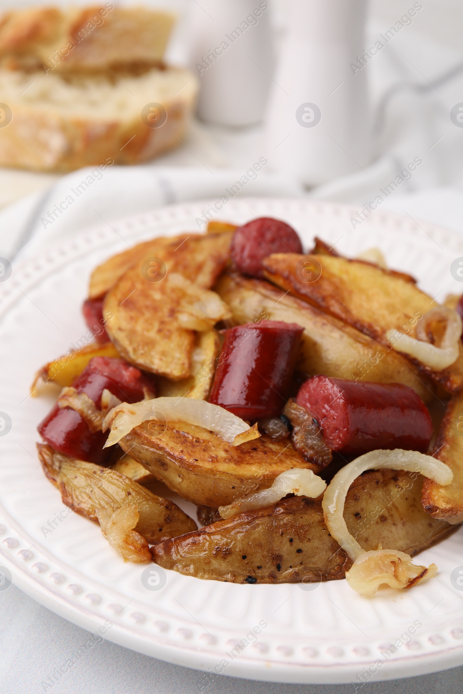 Photo of Delicious baked potato with thin dry smoked sausages and onion on table, closeup