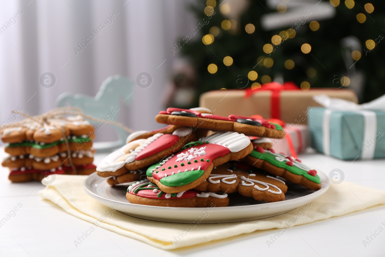 Photo of Decorated cookies on white table against blurred Christmas lights