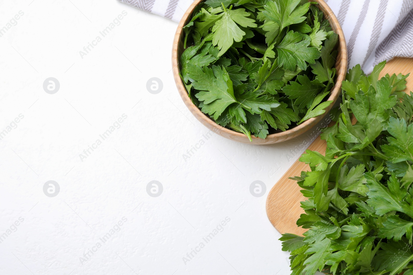 Photo of Wooden board and bowl with fresh green parsley on white table, flat lay. Space for text