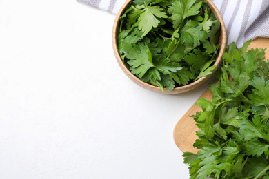 Wooden board and bowl with fresh green parsley on white table, flat lay. Space for text