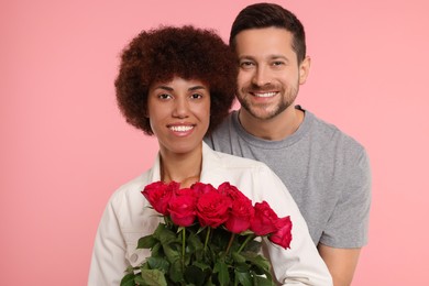 International dating. Lovely couple with bouquet of roses on pink background