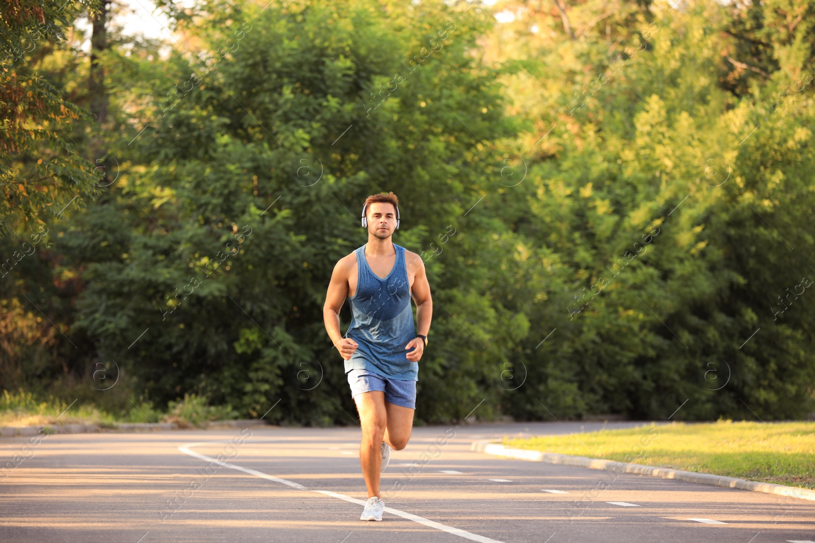 Photo of Young man with headphones running in park